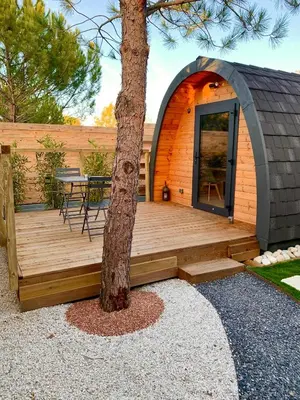 a wooden deck with a table and a tree at A l ombre des pods Chardonnay et spa in Saint-Hilaire