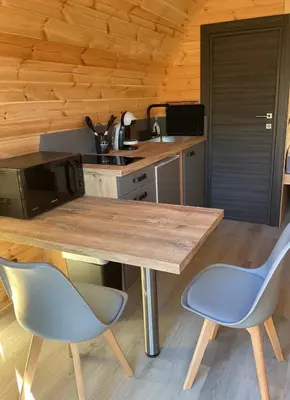 a kitchen with a wooden table and two blue chairs at A l ombre des pods Chardonnay et spa in Saint-Hilaire