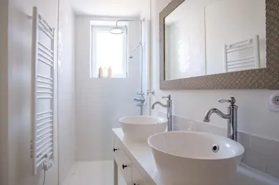 a white bathroom with two sinks and a mirror at Maison Charmante au coeur de la circulade-Patio-AB in Bram