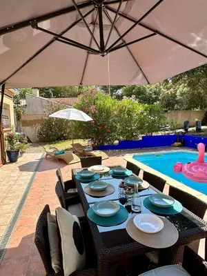a table with chairs and an umbrella next to a swimming pool at Carcassonne Lake & Beach, Pool villa in Carcassonne