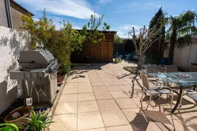 a patio with a table and a grill and a table and chairs at Chez Simon, au fil de l'eau in Revel