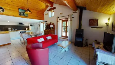 a living room with a red couch and a kitchen at Beau Gîte de Campagne 3 épis in Les Martys
