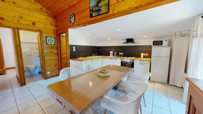 a kitchen with a wooden table and white appliances at Beau Gîte de Campagne 3 épis in Les Martys