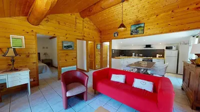 a living room with a red couch and a kitchen at Beau Gîte de Campagne 3 épis in Les Martys