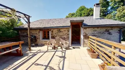 a stone cottage with two chairs and a bench on a patio at Beau Gîte de Campagne 3 épis in Les Martys