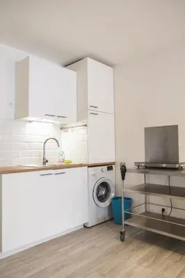 a kitchen with white cabinets and a washing machine at Le Petit Brigantin in Gruissan