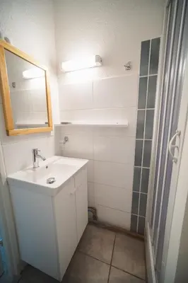 a bathroom with a sink and a mirror and a shower at Le Petit Brigantin in Gruissan