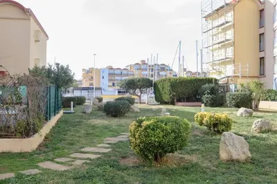 a garden with rocks and bushes and buildings at Le Petit Brigantin in Gruissan