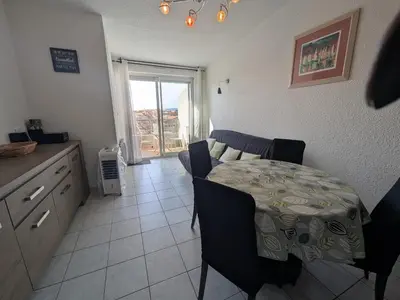 a dining room with a table and a kitchen with a window at Charmant T2 pour 4 pers à 100m de la plage avec balcon - FR-1-797-61 in Port-la-Nouvelle