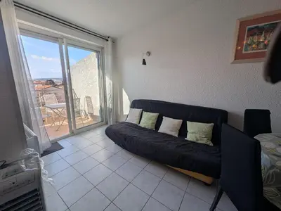 a living room with a couch and a large window at Charmant T2 pour 4 pers à 100m de la plage avec balcon - FR-1-797-61 in Port-la-Nouvelle