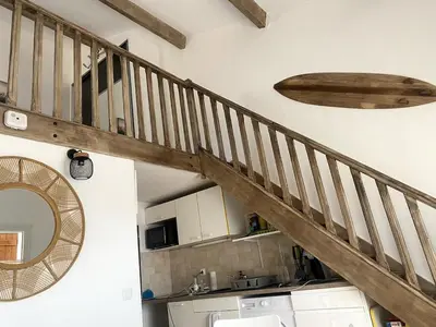 a wooden staircase in a kitchen with a mirror at Maison in Port-la-Nouvelle