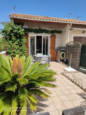a house with a patio with a palm tree at Maison in Port-la-Nouvelle