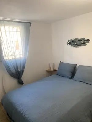 a bedroom with a blue bed and a window at Maison in Port-la-Nouvelle