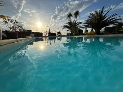 a large pool of blue water with palm trees at Villa T6 d'exception entre Toulouse et Carcassonne , Vue sur les Pyrénées in Trébons-sur-la-Grasse