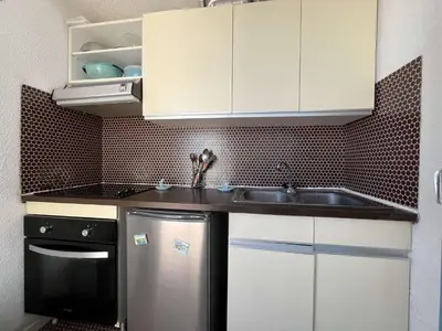 a kitchen with white cabinets and a stainless steel refrigerator at Appartement rénové avec vue marina Gruissan GN140-1033 in Gruissan