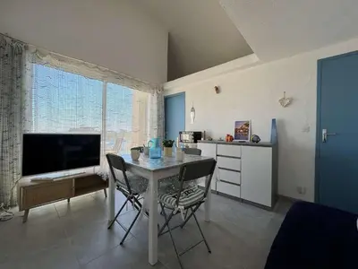 a dining room with a table and a tv and a kitchen at Appartement rénové avec vue marina Gruissan GN140-1033 in Gruissan