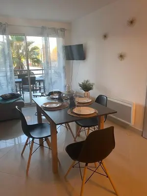 a dining table and chairs in a living room at Appartement tout confort climatisé in Gruissan