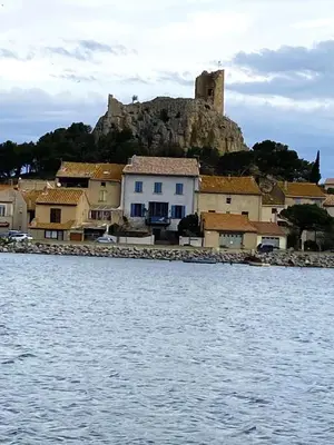 a town with a castle on a hill next to the water at Appartement tout confort climatisé in Gruissan