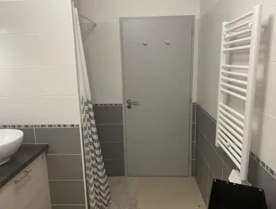 a bathroom with a shower and a white door at Appartement tout confort climatisé in Gruissan
