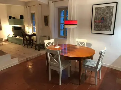 a dining room with a wooden table and chairs at Red sun and green tea in Saint-Jean-de-Barrou