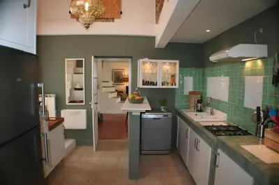 a kitchen with green tiled walls and white cabinets at Red sun and green tea in Saint-Jean-de-Barrou