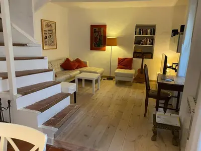 a living room with a staircase and a couch and a table at Red sun and green tea in Saint-Jean-de-Barrou