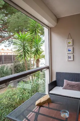 a balcony with a table and a window with a palm tree at L'Escale Marine in Gruissan