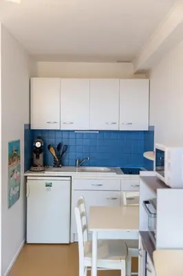 a kitchen with white cabinets and a table with chairs at L'Escale Marine in Gruissan