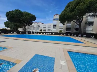a large swimming pool with chairs in front of a building at L'Escale Marine in Gruissan