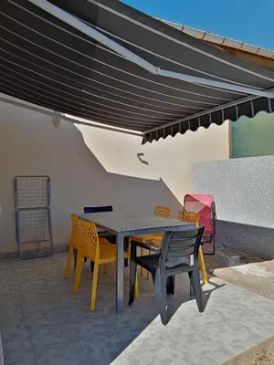 a patio with a table and chairs under awning at Charmant gîte au coeur des Corbières in Tuchan