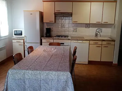 a kitchen with a table and a white refrigerator at Charmant gîte au coeur des Corbières in Tuchan