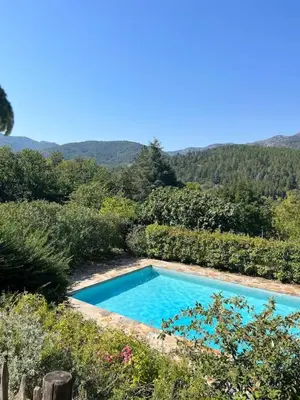a swimming pool in a garden with mountains in the background at Stylish villa with large pool and stunning views in Olargues