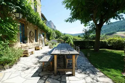 an old stone house with blue windows and a road at Le Presbytère de Bugarach in Bugarach