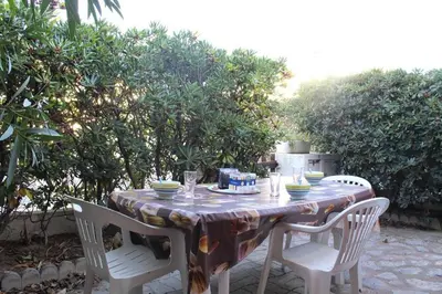 a table with two chairs and a table with dishes on it at Maison 4 pièces 8 couchages PORT LA NOUVELLE PN000-001 in Port-la-Nouvelle