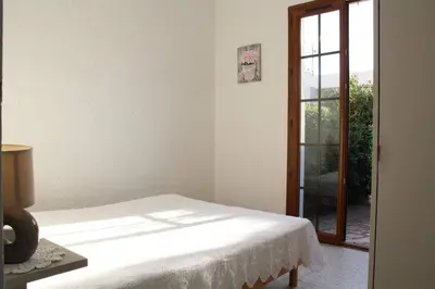 a bedroom with a bed and a sliding glass door at Maison 4 pièces 8 couchages PORT LA NOUVELLE PN000-001 in Port-la-Nouvelle
