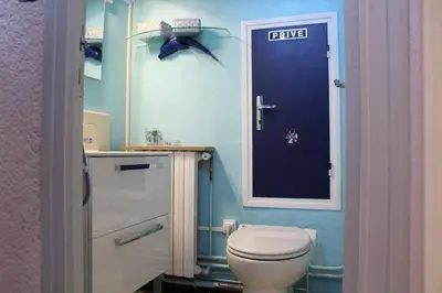 a bathroom with a toilet and a blue door at Maison 4 pièces 8 couchages PORT LA NOUVELLE PN000-001 in Port-la-Nouvelle