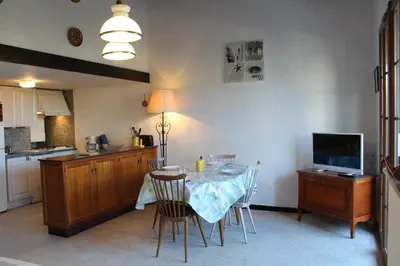 a kitchen with a table with chairs and a television at Maison 4 pièces 8 couchages PORT LA NOUVELLE PN000-001 in Port-la-Nouvelle