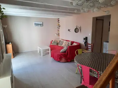 a living room with a red couch and a table at Maison Gruissan village 90m2 avec jardin a 1km de la plage in Gruissan