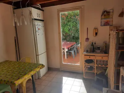 a kitchen with a table and a refrigerator and a table with a table at Maison Gruissan village 90m2 avec jardin a 1km de la plage in Gruissan