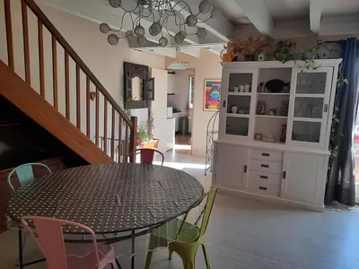 a dining room with a table and chairs and a cabinet at Maison Gruissan village 90m2 avec jardin a 1km de la plage in Gruissan