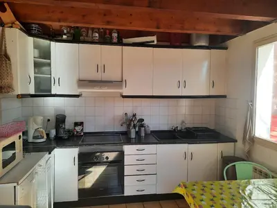 a kitchen with white cabinets and black counter tops at Maison Gruissan village 90m2 avec jardin a 1km de la plage in Gruissan