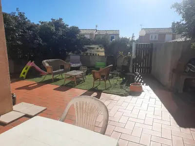 a backyard with chairs and a table and a playground at Maison Gruissan village 90m2 avec jardin a 1km de la plage in Gruissan