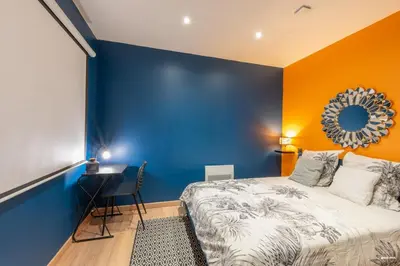 a blue and orange bedroom with a bed and a desk at La tavernne de Balaach Clim Wifi Cozy in Carcassonne