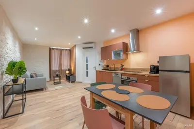 a kitchen and living room with a table and a refrigerator at La tavernne de Balaach Clim Wifi Cozy in Carcassonne