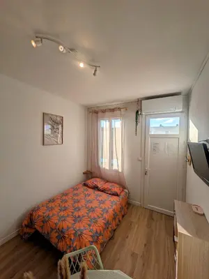 a small bedroom with a bed and a door at LE LOGIS, T2 au pied de la plage, Climatisation in Port-la-Nouvelle