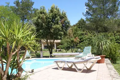 a swimming pool with two lawn chairs and trees at Manor Norbert in Ventenac-Cabardès