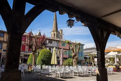 a group of tables and chairs in front of a building at La petite maison au grand parc in Rieux-de-Pelleport