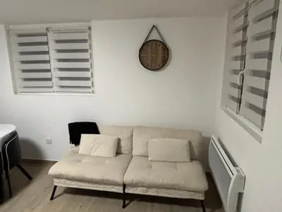 a living room with a couch and a clock on the wall at Petite maison au calme in Pont-de-Larn