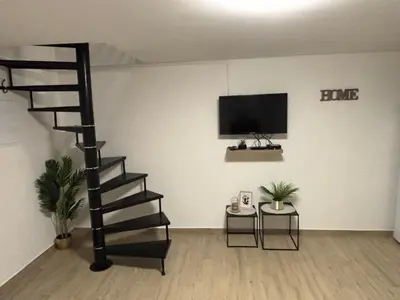 a living room with a spiral staircase and a tv at Petite maison au calme in Pont-de-Larn