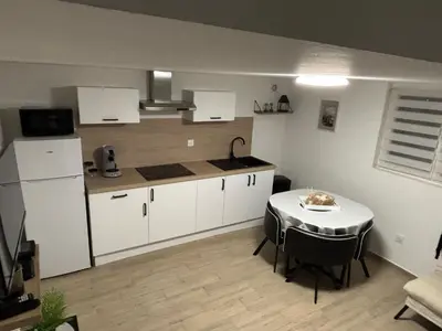 a kitchen with a table and a kitchen with white cabinets at Petite maison au calme in Pont-de-Larn